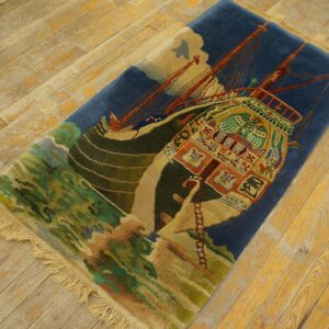 Deep blue rug with a striking colorful ship design and green waves rests on worn wood flooring.