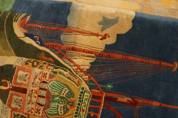 High-pile rug with abstract dark blue and orange forms, surrounded by green and multicolored geometric motifs on wood floor.