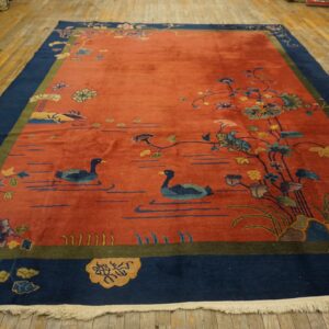 A low-pile, rust and blue scenic rug showing ducks and flowers, laid upon distressed wooden planks.