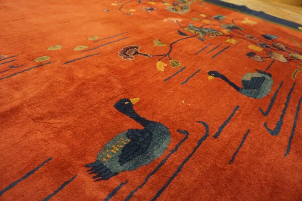 Rust-toned rug with deep pile features a pictorial pattern of blue geese, vines, and scattered florals.
