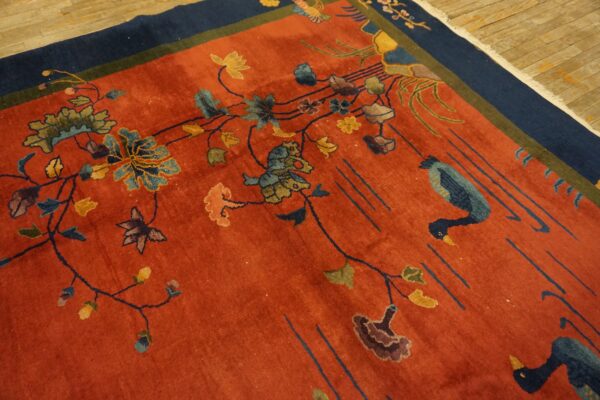 Rust field rug with stylized blue birds, colorful floral vines, and a contrasting navy blue border.