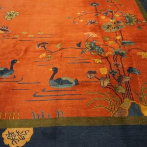 Orange rug with a navy border features a detailed scene of two ducks swimming among flowering vines.