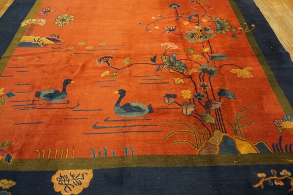 Orange rug with a navy border features a detailed scene of two ducks swimming among flowering vines.