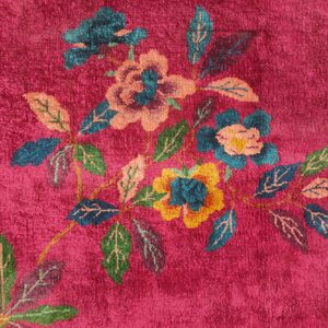 Detail of a plush magenta rug featuring large floral and leafy patterns in multicolor tones.