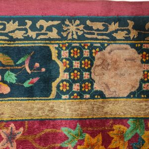 Ornate rug border featuring floral motifs and geometric patterns in deep magenta, teal, and gold.