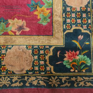 Ornate rug corner showing a magenta field, teal border, colorful floral motifs, and geometric patterns.