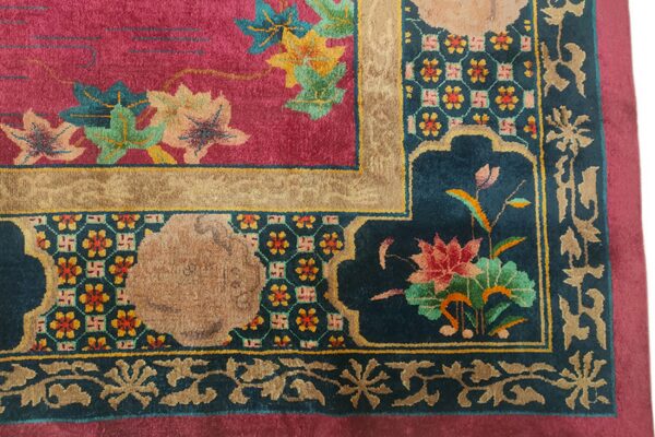 Ornate rug corner showing a magenta field, teal border, colorful floral motifs, and geometric patterns.