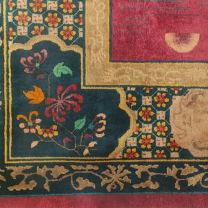 A magenta, tan, and teal high-pile rug corner displaying complex floral and geometric patterns.