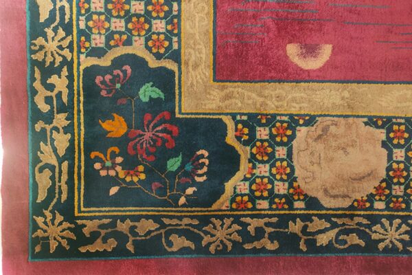 A magenta, tan, and teal high-pile rug corner displaying complex floral and geometric patterns.