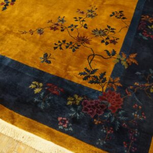 High-pile golden yellow and navy rug featuring a lush floral and branch pattern on light hardwood.