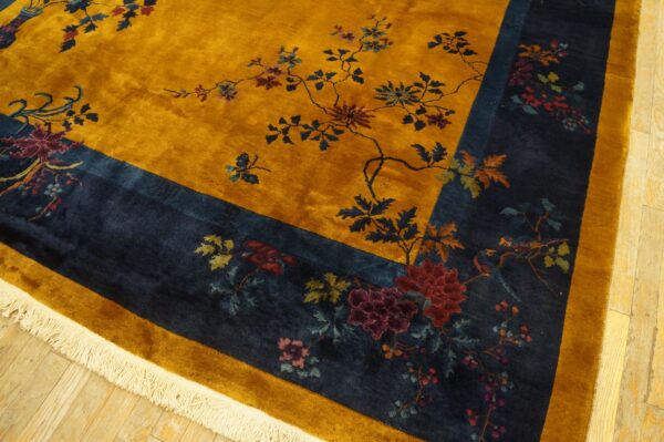 High-pile golden yellow and navy rug featuring a lush floral and branch pattern on light hardwood.