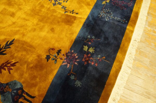 Gold and indigo rug featuring intricate floral designs and visible high pile on a light wood floor.