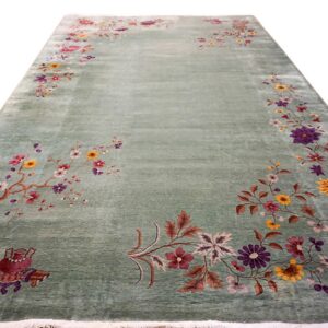 Long sage green rug featuring multicolored floral vines, vases, and decorative motifs around an open field.