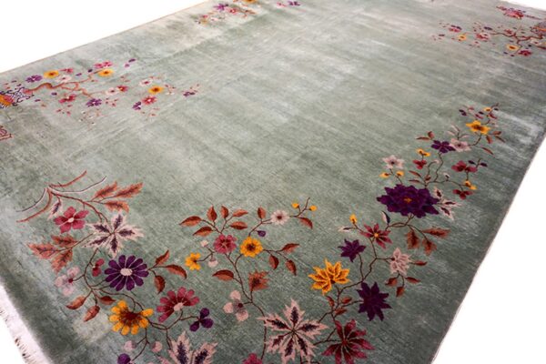 Striated sage green rug with scattered floral motifs in purple, yellow, and pink on a white background.