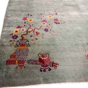 Muted green rug detailed with colorful blossoming branches, ornate vases, and decorative objects.