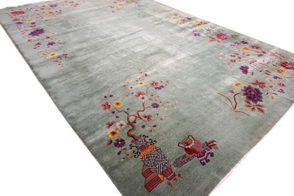 Pale green rug with colorful floral motifs, including pink blossoms and stylized decorative objects.