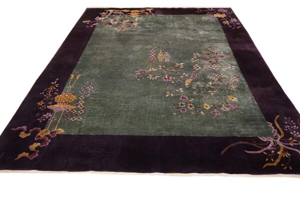 Rectangular rug featuring a sage green field framed by a wide deep purple border with floral and bird designs.