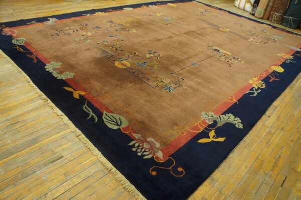 Low-pile brown rug featuring colorful floral designs and a dark blue border on yellow wood floors.