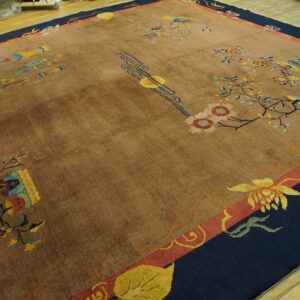 Brown rug with a bold navy and coral border and scattered Art Deco floral designs on a wood floor.
