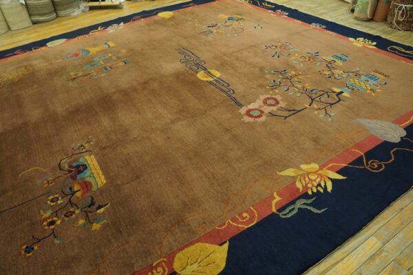 Brown rug with a bold navy and coral border and scattered art deco floral designs on a wood floor.