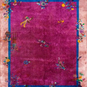 High-pile magenta rug with a wide beige border and blue trim features bright multicolored floral and bird motifs.