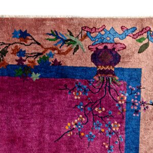High-pile rug corner detail in magenta and pink with a blue border, featuring stylized leaves and floral branches.