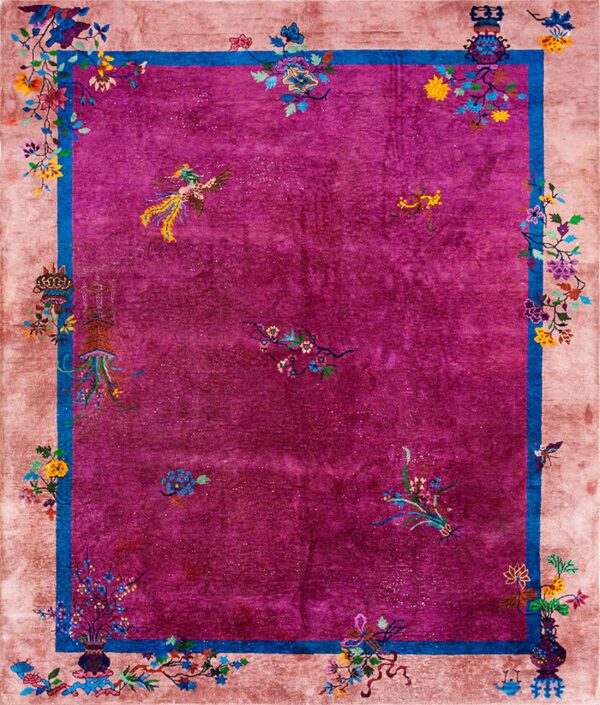 High-pile magenta rug with a wide beige border and blue trim features bright multicolored floral and bird motifs.