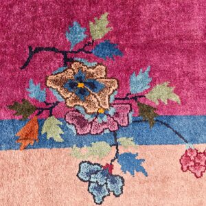 High pile rug with magenta background, blue border, and colorful carved floral design.