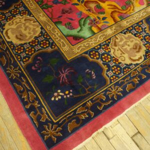 High-pile rug corner showing navy, magenta, and gold borders with detailed floral and animal patterns over wood.