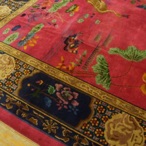 A brightly colored magenta rug with floral and bird designs sits on light hardwood flooring.