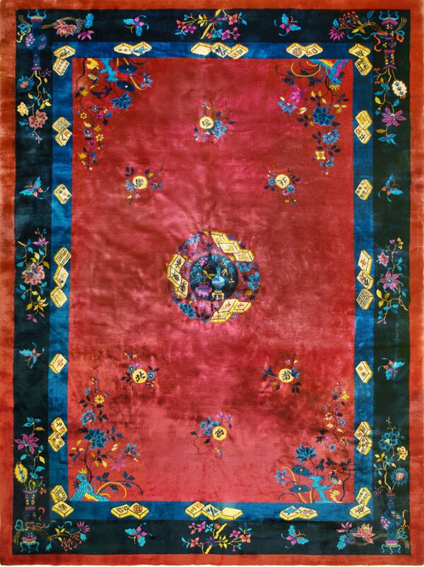 Rich red rug with dark teal and blue borders showing intricate florals, vases, and game tile motifs.