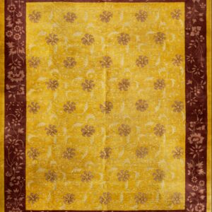 Gold rug with low-contrast botanical designs surrounded by a deep burgundy floral border.