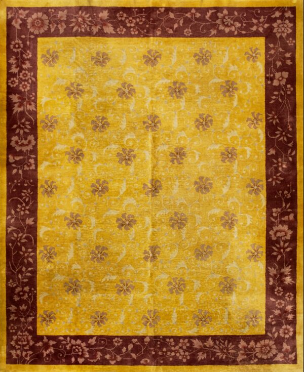 Gold rug with low-contrast botanical designs surrounded by a deep burgundy floral border.