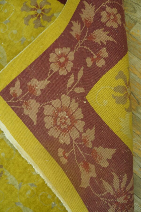 Folded rug showing chartreuse high-pile field, and a burgundy border with beige florals and a yellow stripe.