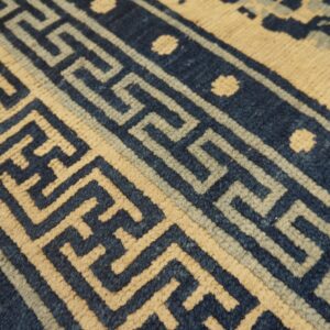 Geometric rug border featuring navy blue, light blue, and cream colors in a repeating fret pattern.