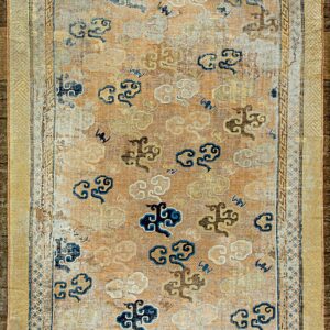 Tan and beige low-pile rug featuring scattered blue and gold stylized cloud patterns and complex gold borders.