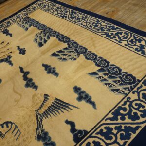 Cream rug with a blue decorative border and avian pattern laid over rustic wood planks.