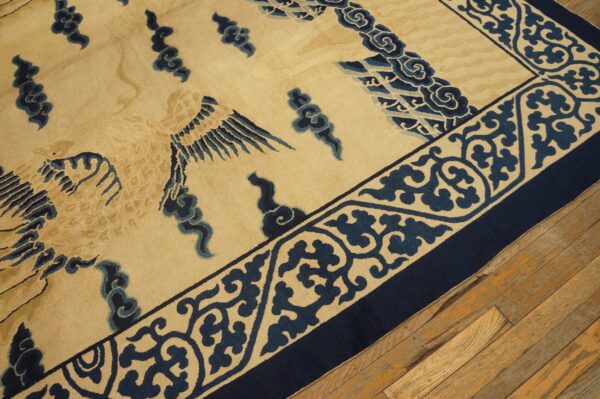 High-pile tan rug featuring large stylized blue birds and clouds, detailed borders, resting on worn wooden floorboards.