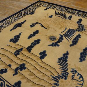 Gold and dark blue rug featuring a central avian motif, clouds, and ornate scrolling border on wood floors.