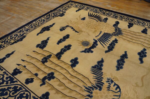 Gold and dark blue rug featuring a central avian motif, clouds, and ornate scrolling border on wood floors.