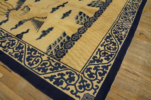 Beige and navy rug featuring a bird and cloud motifs, detailed border, resting on wood planks.