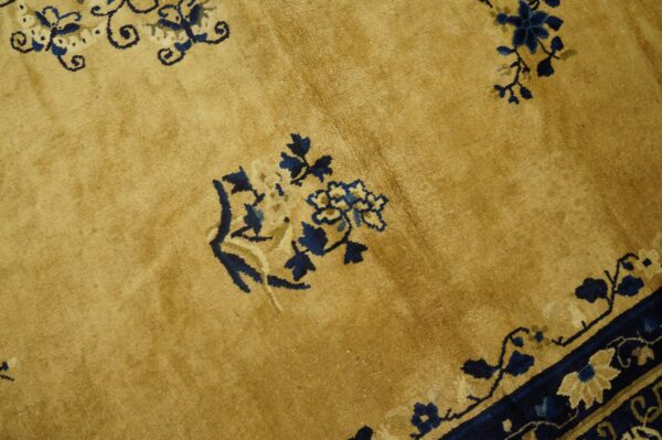 Detail shot of a gold rug with high pile and stylized navy and beige floral designs.
