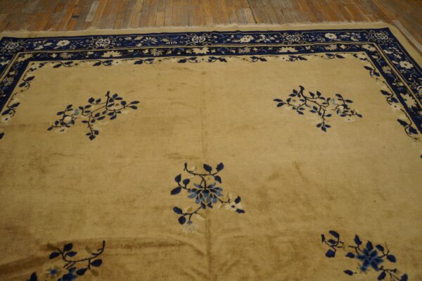 A tan rug with navy and cream ornate borders and scattered blue floral patterns rests on wood floors.