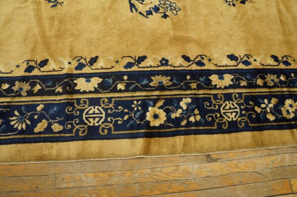 Golden yellow rug with a wide navy blue border featuring intricate light blue and tan floral patterns on wood flooring.