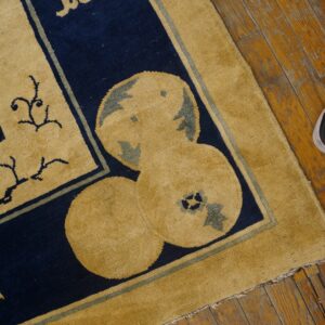 Stylized mustard yellow and navy blue rug featuring ornate patterns rests on distressed wood plank flooring.