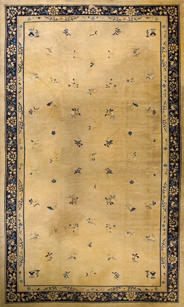 Tan rug with scattered blue and yellow sprigs, framed by a thick dark blue floral border.