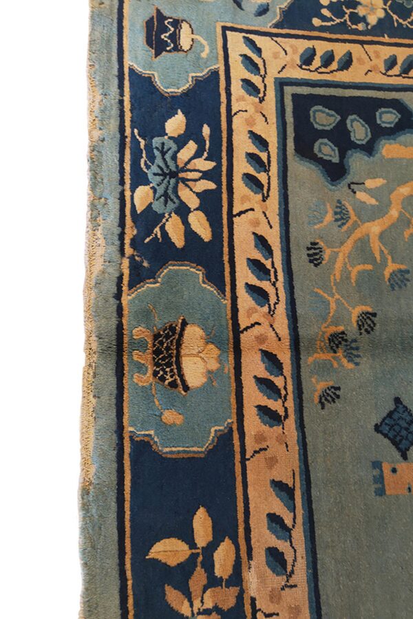 Ornate rug border in navy blue, dusty teal, and tan with stylized leaves and cartouches.