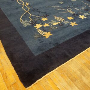 Dark blue rug featuring a light-colored grapevine pattern and a thick navy border on a wood floor.