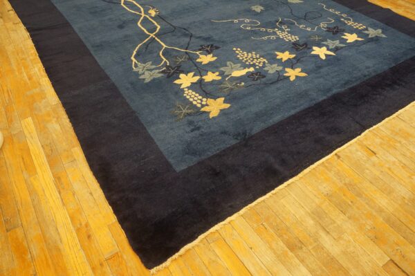 Dark blue rug featuring a light-colored grapevine pattern and a thick navy border on a wood floor.