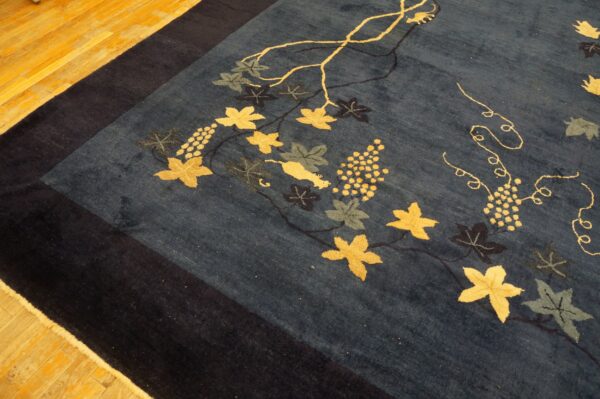 Deep blue rug with gold and green grapevine motifs on light wood plank flooring.